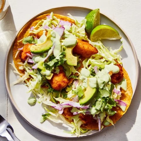 Golden Baja Fish Tacos filled with crunchy white fish, avocado slices, and pickled onions, served with warm corn tortillas.