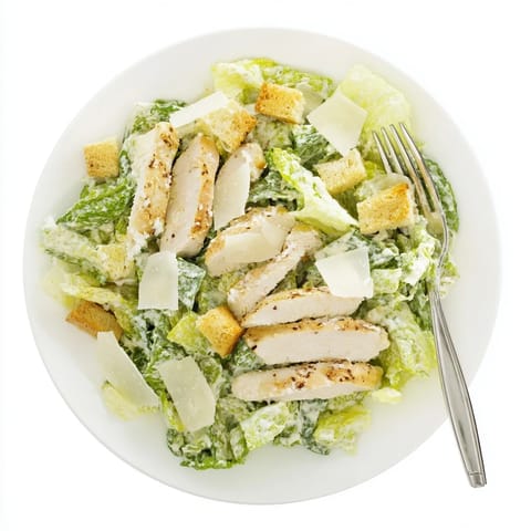 Golden croutons and creamy dressing garnish this hearty Chicken Caesar Salad, served ready to enjoy on a rustic plate.