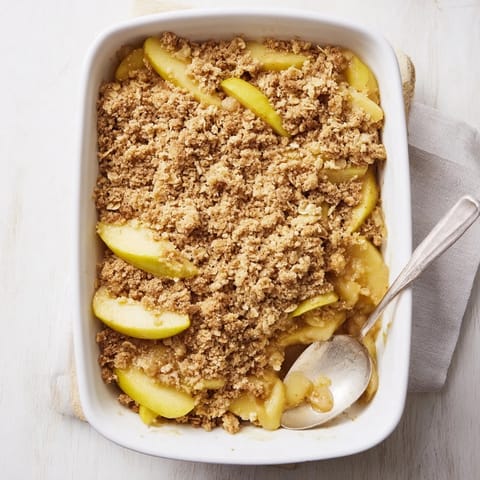 Freshly baked Apple Crumble with tender cinnamon apples and a golden oat topping, ready to serve warm with vanilla ice cream.