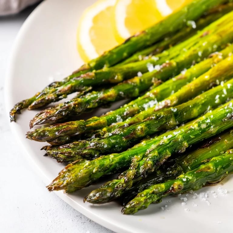 Golden charred asparagus spears arranged on a serving platter with lemon wedges, ready to be enjoyed.