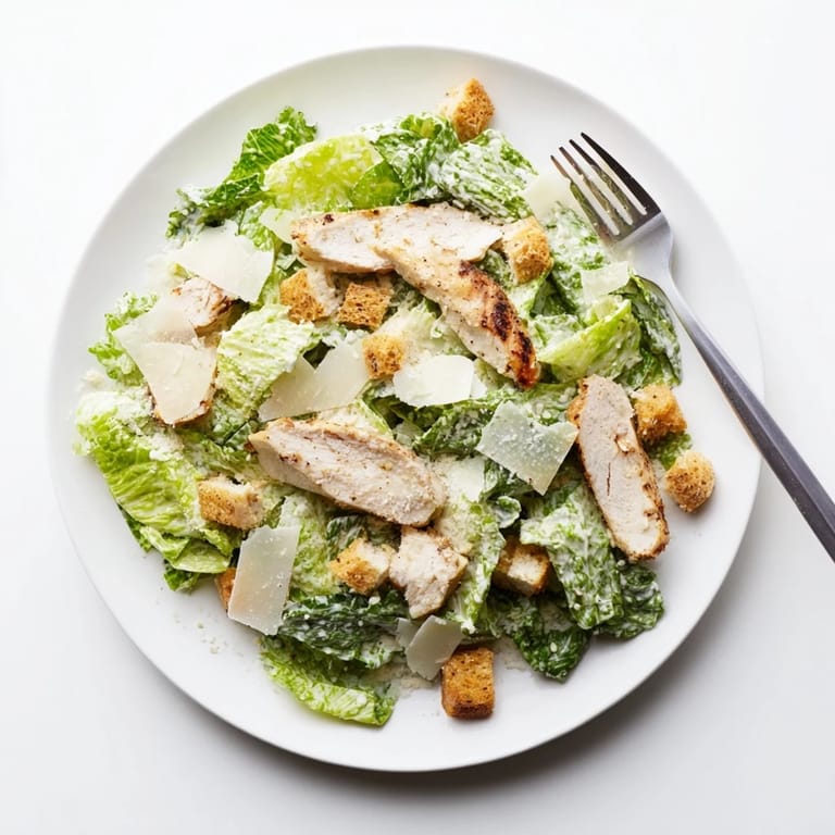 Juicy grilled chicken crowns a vibrant bowl of Chicken Caesar Salad, featuring crunchy croutons and rich Parmesan shavings.