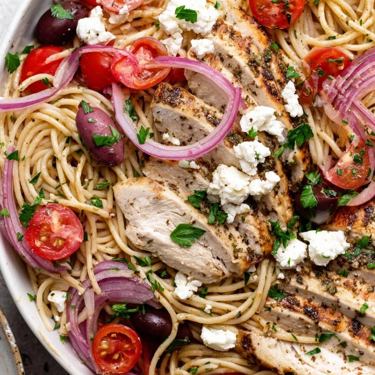 Savory Greek Chicken Spaghetti features al dente noodles, grilled chicken, red onion, and parsley finished with a bright lemon dressing.