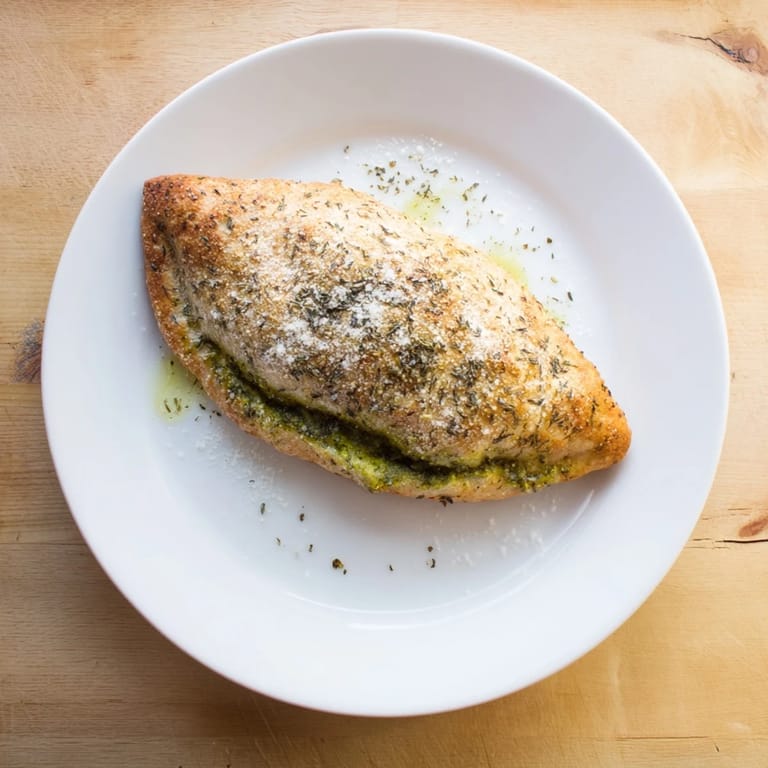 Juicy Mozzarella & Pesto Stuffed Chicken resting in a baking dish, topped with golden Parmesan and herbs.