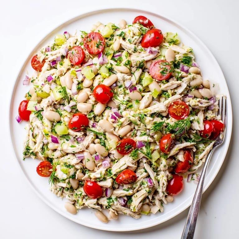 Lemony White Bean Chicken Salad served on a bed of crisp greens with juicy cherry tomatoes and diced celery for a light lunch.