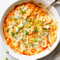 Golden, bubbly Buffalo Chicken Dip emerges from the oven with melted cheese and chopped chives.