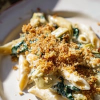 A golden-brown Artichoke Pasta Bake fresh from the oven, showing bubbly cheese and golden breadcrumbs on top.
