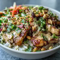 Golden sautéed chicken and vibrant red cabbage top fluffy coconut rice in this hearty Peanut Chicken Protein Bowl, garnished with fresh cilantro and lime wedges.