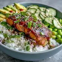 Flaky pan-seared salmon glazed in honey sriracha, nestled on jasmine rice with crisp cucumber slices.