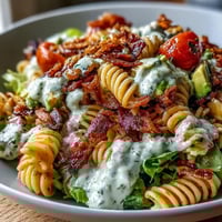 Vibrant BLT pasta with avocado ranch, showcasing crispy bacon, fresh lettuce, and cherry tomatoes in a creamy dressing.  